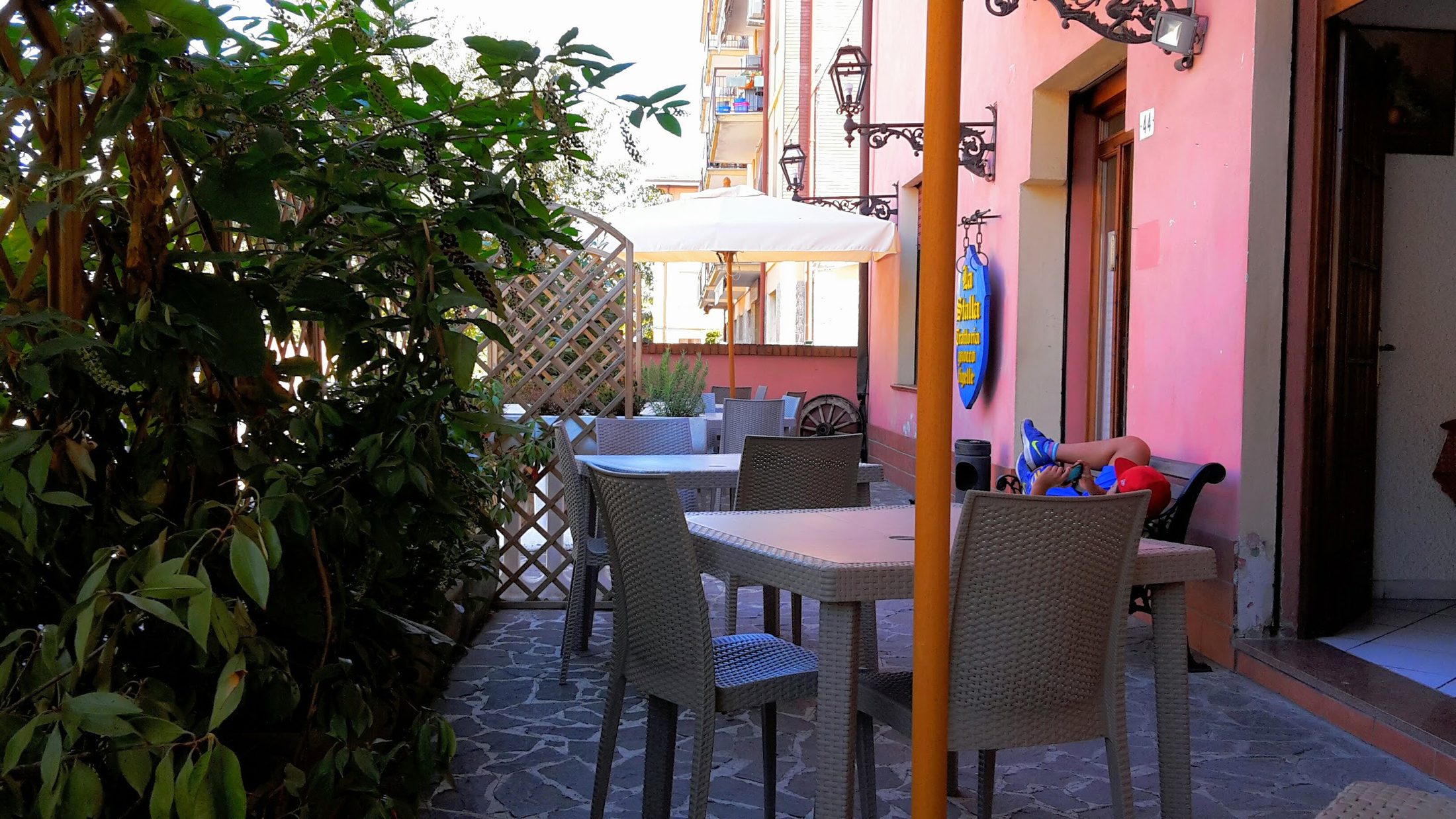 Il dehors della Trattoria La Stalla con l'insegna di legno blu e oro appesa alla facciata rosa